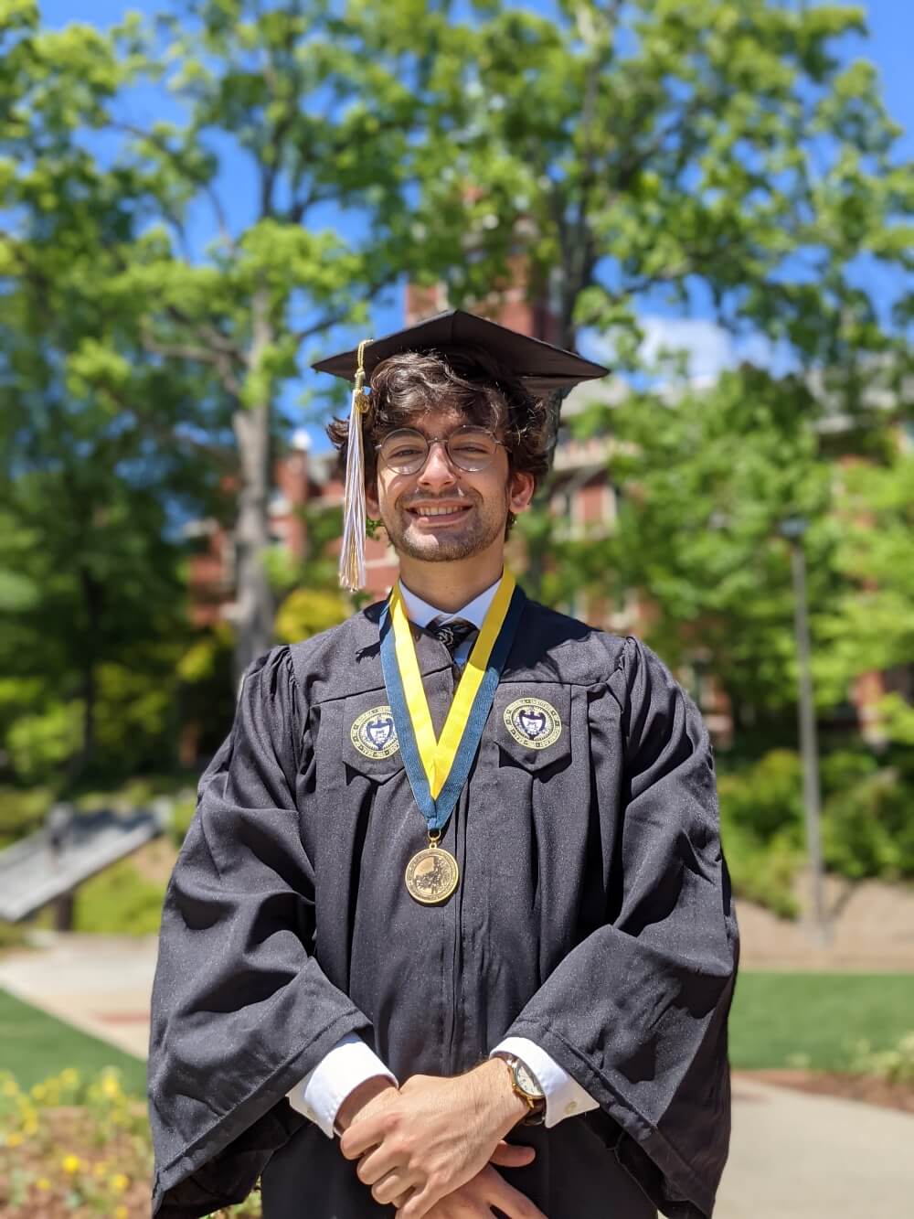 A picture of me standing in front of Tech Tower in my graduation regalia looking at the camera.
